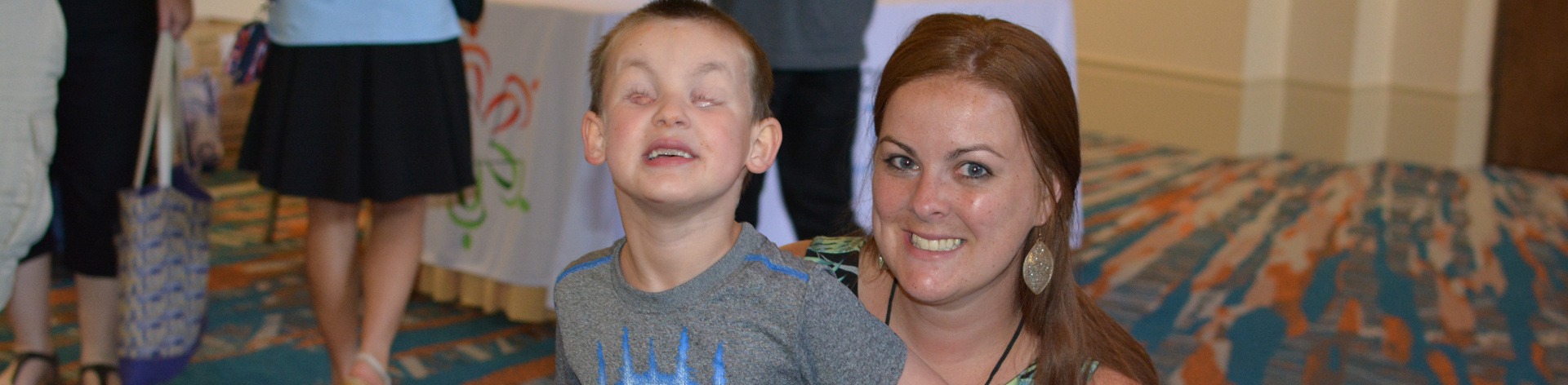 A mother smiles with her blind son at convention.